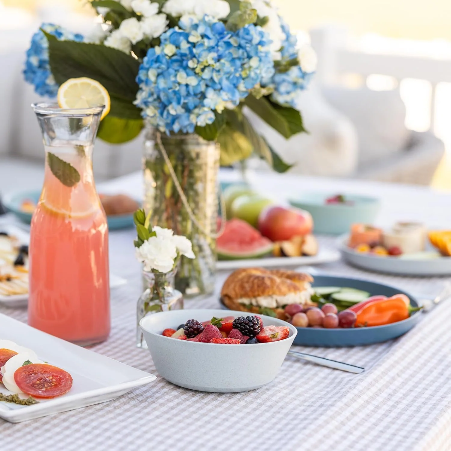 Two-color wheat straw plate and bowl set used at a bright outdoor picnic table with blue plates and bowls